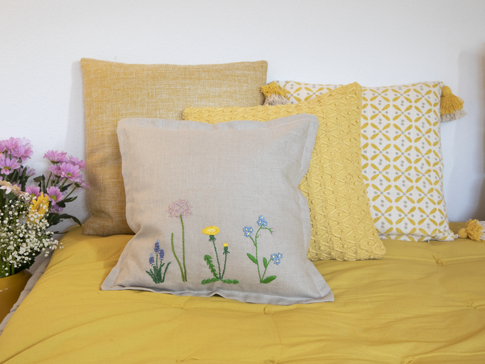 Mit den Blumenstickereien holst du dir den Frühling ins Haus. Blumenstickereien auf Kissen auf einem Bett
